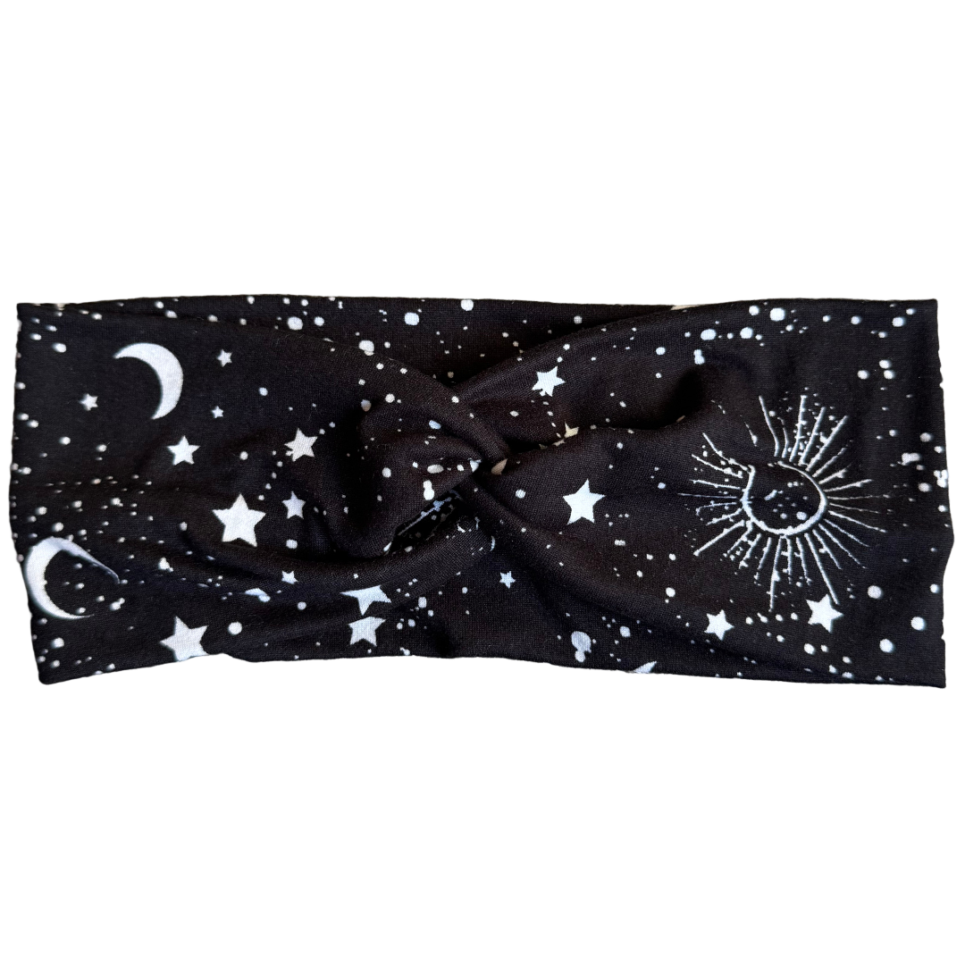 Black headband with celestial designs on a textured gray surface