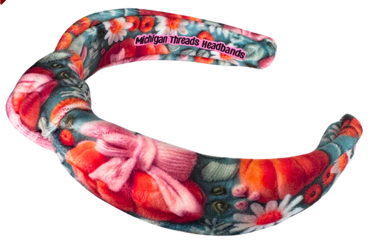 A knotted headband with a pumpkin bow design, featuring a floral pattern with colors pink, orange, and green, and the text 'Michigan Threads Headbands'.