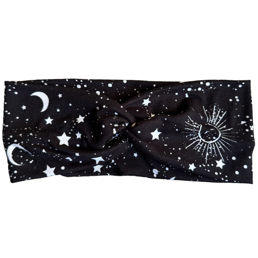 Black headband with celestial designs on a textured gray surface